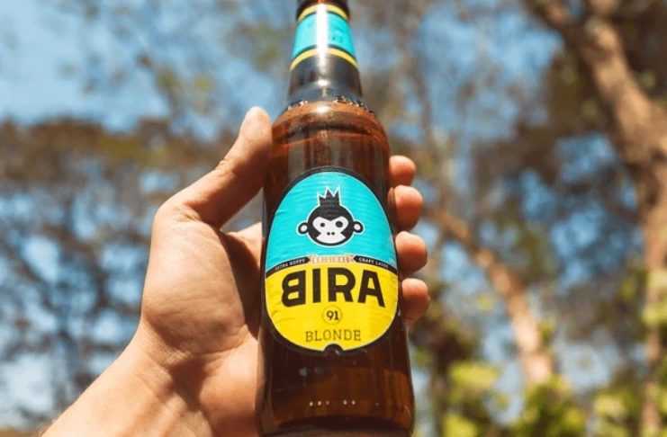 Hand holding Bira 91 beer bottle